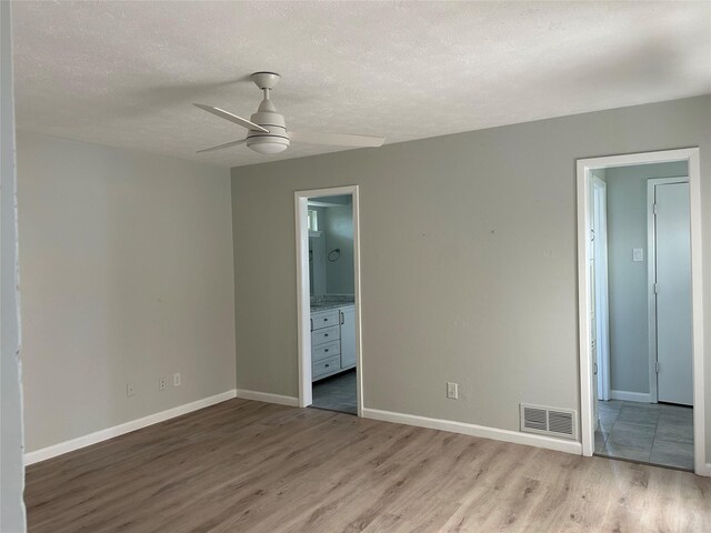 1104 Hillsdale Dr, Richardson, TX 75081 - unfurnished bedroom with light wood finished floors, a textured ceiling, baseboards, connected bathroom, and ceiling fan