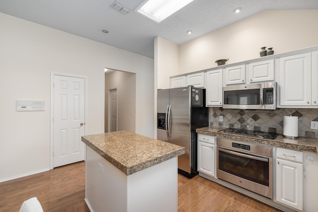 kitchen featuring stainless steel appliances, decorative backsplash, a center island, light wood finished floors, and white cabinets