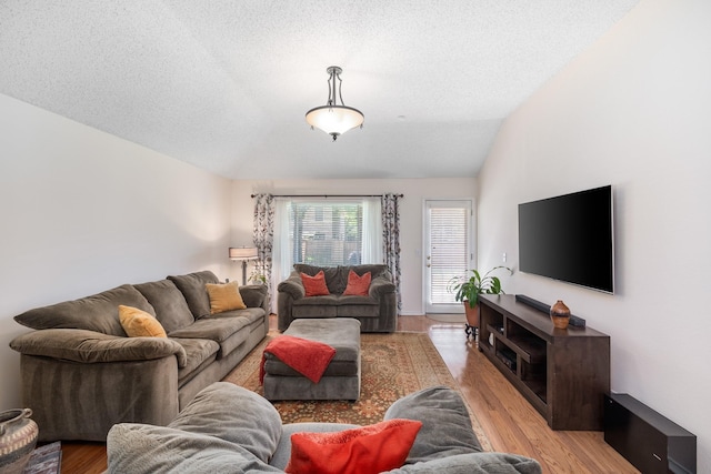 living area with light wood-type flooring, a textured ceiling, and lofted ceiling