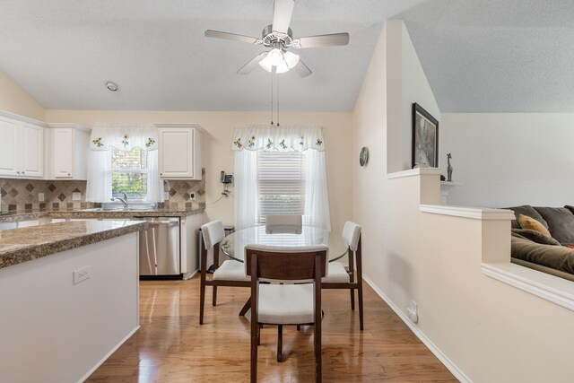 dining space featuring vaulted ceiling, light wood finished floors, ceiling fan, and baseboards