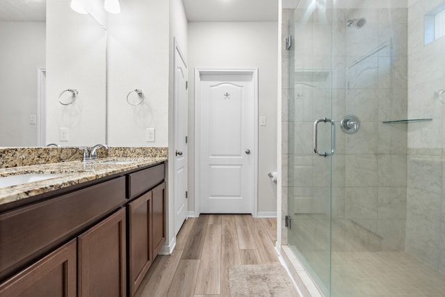 full bathroom with a shower stall, wood finished floors, vanity, and baseboards