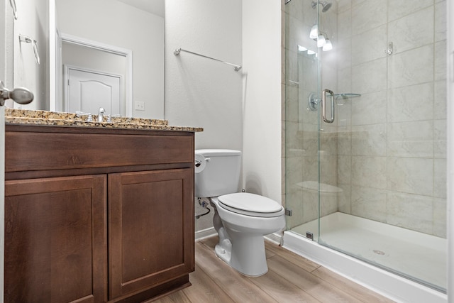 full bath with wood finished floors, a shower stall, toilet, vanity, and baseboards