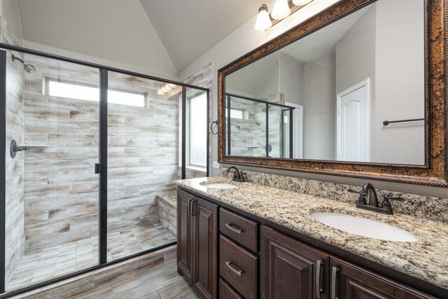 full bathroom featuring vaulted ceiling, a stall shower, double vanity, and wood finished floors