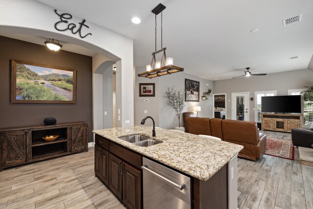 kitchen with stainless steel dishwasher, a sink, light wood finished floors, arched walkways, and a ceiling fan