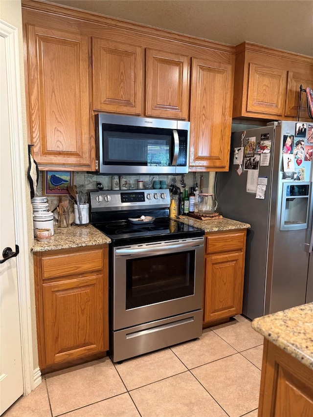103 Apache Ct, Glen Rose, TX 76043 - kitchen with stainless steel appliances, brown cabinets, and light tile patterned floors