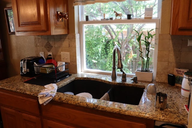 103 Apache Ct, Glen Rose, TX 76043 - kitchen featuring backsplash, a sink, and brown cabinetry