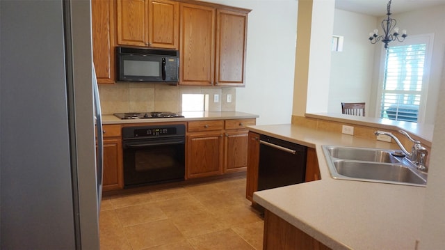 kitchen with black appliances, a sink, decorative backsplash, a chandelier, and light countertops
