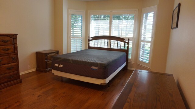 bedroom with wood finished floors, multiple windows, and baseboards