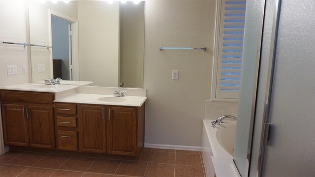 full bath featuring double vanity, tile patterned flooring, a bath, and baseboards