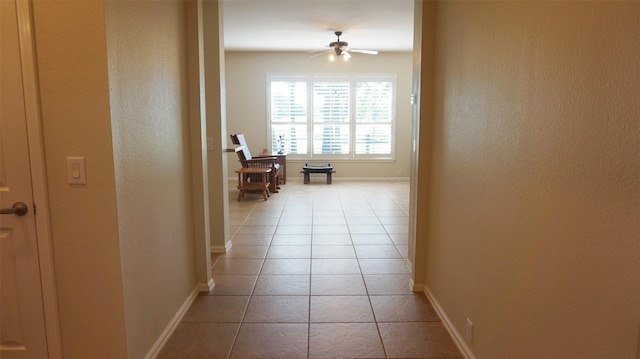 hall with baseboards, light tile patterned floors, and a textured wall
