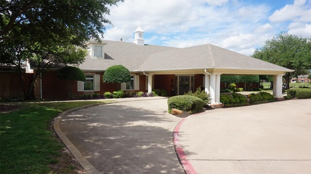 view of front of property with curved driveway, a chimney, and fence