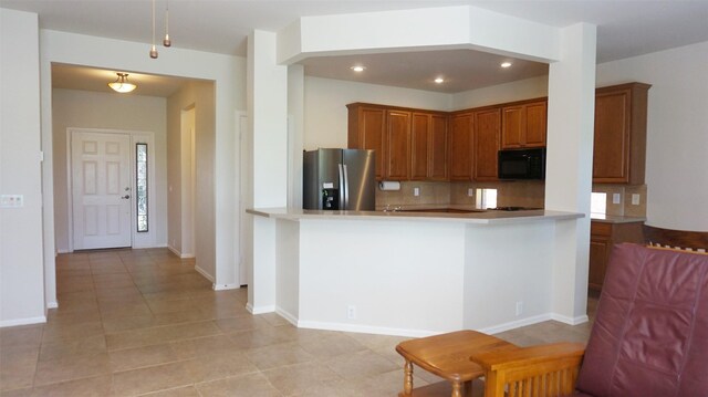 kitchen featuring stainless steel fridge with ice dispenser, black microwave, decorative backsplash, brown cabinetry, and recessed lighting