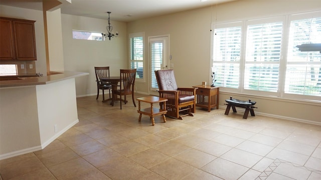 sitting room featuring plenty of natural light, light tile patterned floors, a chandelier, and baseboards