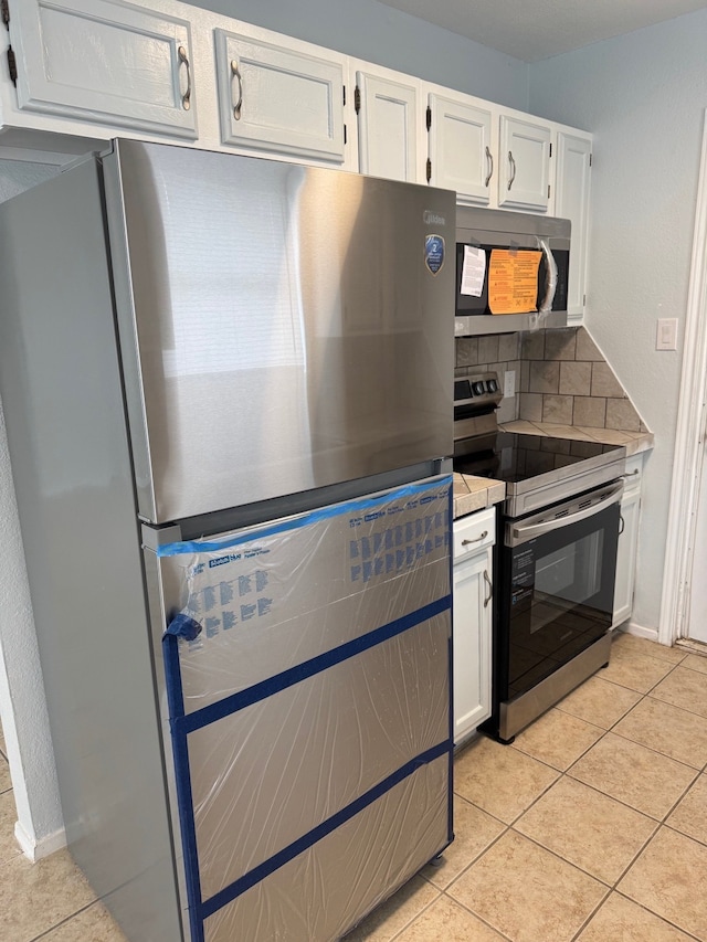 3902 Georgetown Dr, Abilene, TX 79602 - kitchen featuring stainless steel appliances, decorative backsplash, white cabinetry, and light tile patterned floors