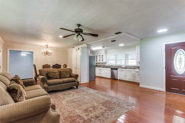 living room with ceiling fan, a chandelier, crown molding, wood finished floors, and a textured ceiling