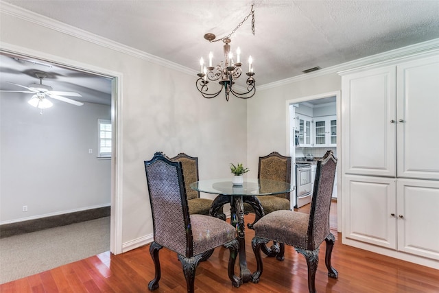 dining area featuring a chandelier, wood finished floors, baseboards, ornamental molding, and a ceiling fan