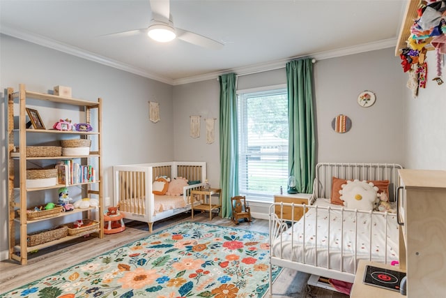 bedroom with ornamental molding, wood finished floors, multiple windows, radiator heating unit, and ceiling fan