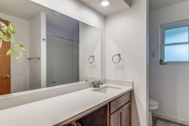 bathroom with toilet, baseboards, vanity, and a shower