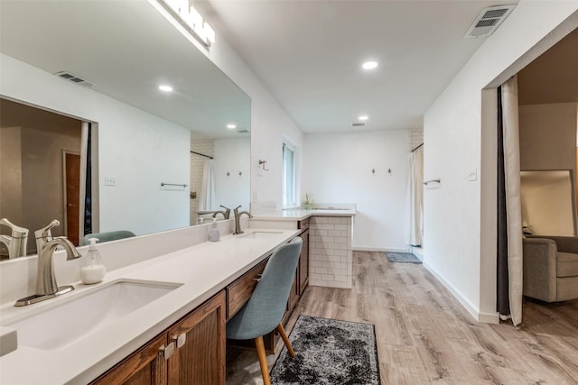 bathroom with wood finished floors, a shower, recessed lighting, and double vanity