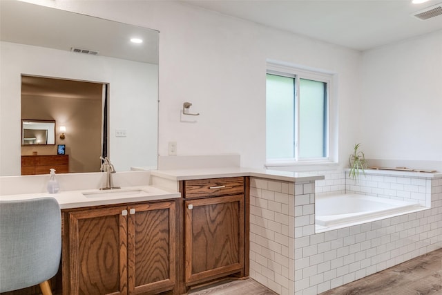 full bathroom with wood finished floors, vanity, a garden tub, and recessed lighting