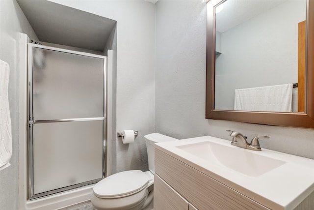 full bathroom featuring a shower stall, toilet, vanity, and a textured wall