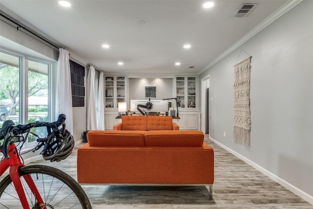 living area with ornamental molding, recessed lighting, light wood-style floors, baseboards, and built in shelves