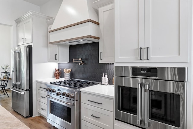 9001 Emma Ct, Granbury, TX 76049 - kitchen featuring high end appliances, custom exhaust hood, light countertops, white cabinetry, and backsplash