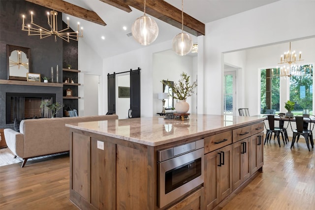 9001 Emma Ct, Granbury, TX 76049 - kitchen featuring a chandelier, stainless steel microwave, a barn door, beamed ceiling, and wood finished floors