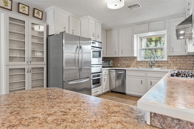 4325 Shady Glen Dr, Waco, TX 76708 - kitchen featuring appliances with stainless steel finishes, a sink, white cabinets, light countertops, and tasteful backsplash