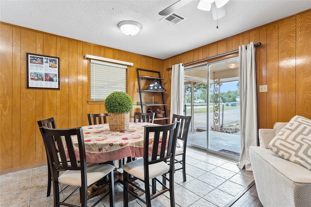 4325 Shady Glen Dr, Waco, TX 76708 - dining area with wooden walls, ceiling fan, a textured ceiling, and light tile patterned floors