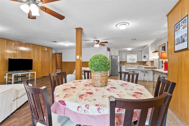 4325 Shady Glen Dr, Waco, TX 76708 - dining room featuring ceiling fan, wood walls, a textured ceiling, and wood finished floors
