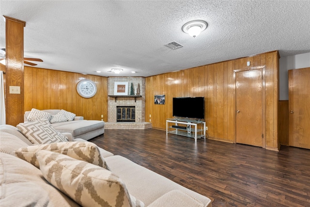 4325 Shady Glen Dr, Waco, TX 76708 - living area featuring a textured ceiling, wood walls, wood finished floors, a brick fireplace, and ceiling fan