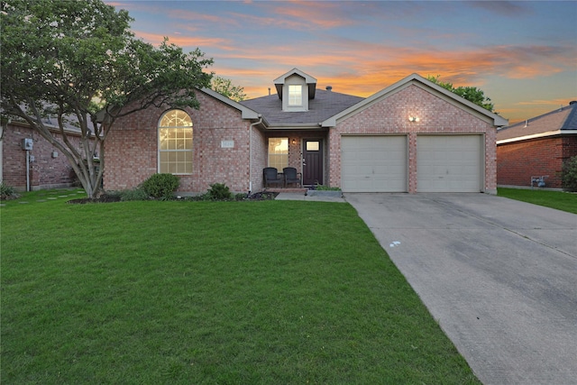 traditional-style house with an attached garage, concrete driveway, a lawn, and brick siding
