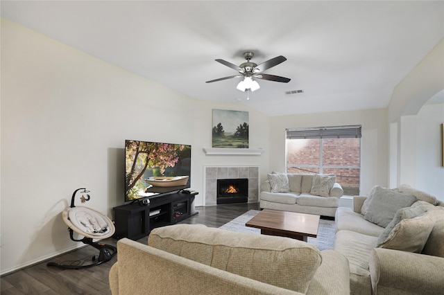 living area with dark wood finished floors, a ceiling fan, a fireplace, baseboards, and arched walkways
