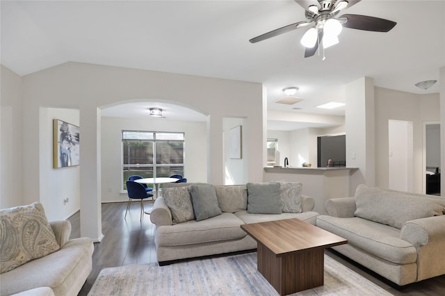living room with arched walkways, wood finished floors, ceiling fan, and vaulted ceiling