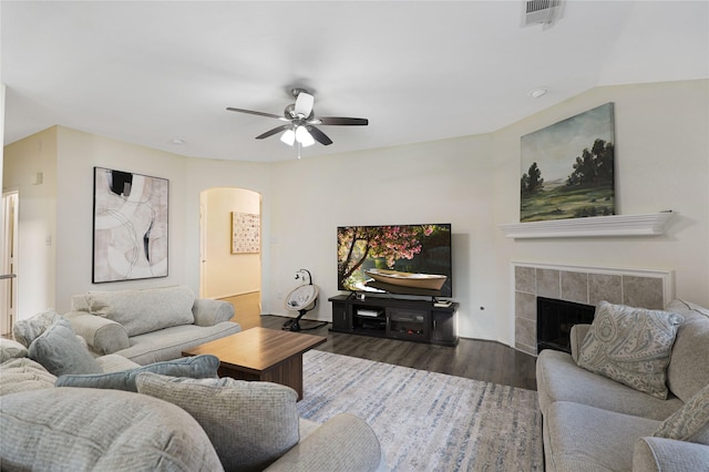 living room with wood finished floors, ceiling fan, arched walkways, and a fireplace
