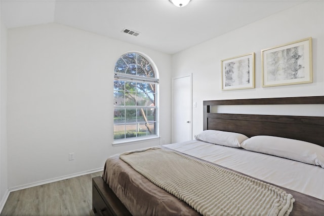 bedroom featuring wood finished floors, baseboards, and vaulted ceiling