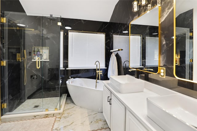 full bathroom with marble tiled floors, a marble finish shower, a freestanding bath, double vanity, and tile walls