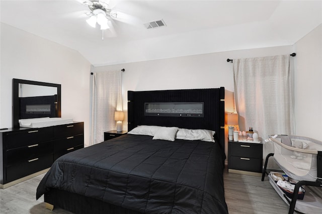 bedroom with light wood-style floors, vaulted ceiling, and a ceiling fan