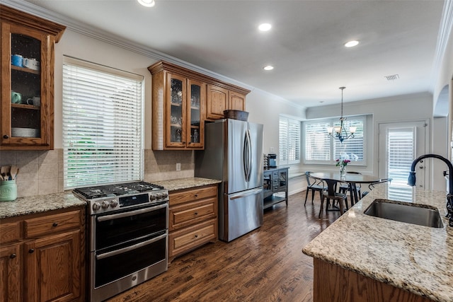 kitchen featuring appliances with stainless steel finishes, a sink, crown molding, brown cabinetry, and dark wood-type flooring