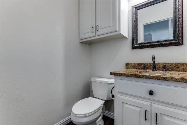 half bath with vanity, toilet, and baseboards