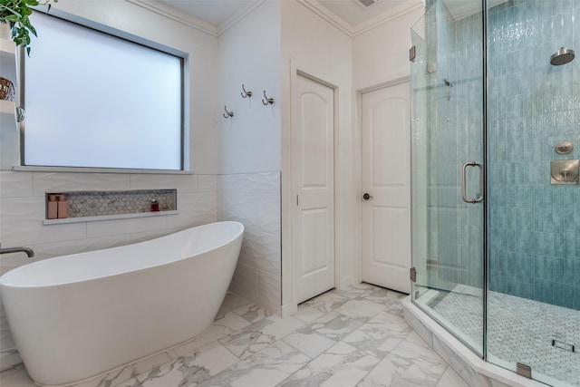 bathroom with a shower stall, crown molding, a soaking tub, marble finish flooring, and tile walls