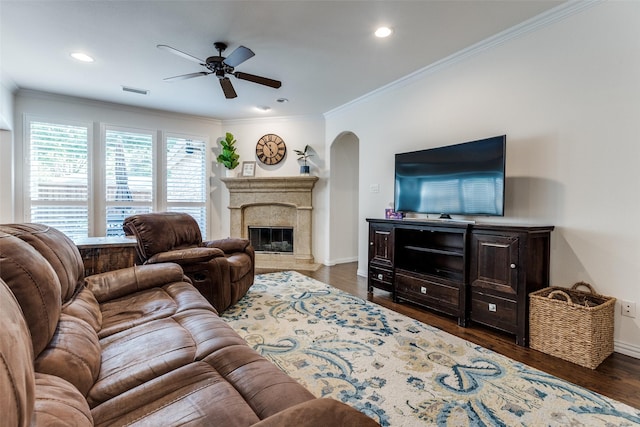living room featuring arched walkways, a ceiling fan, crown molding, baseboards, and wood finished floors