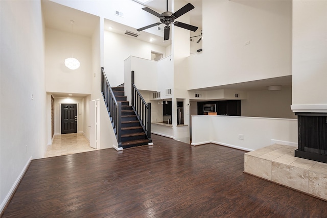 6808 Eastridge Dr Unit A7, Dallas, TX 75231 - unfurnished living room featuring a high ceiling, ceiling fan, wood finished floors, stairs, and baseboards