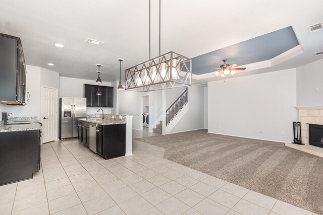 kitchen featuring stainless steel appliances, open floor plan, a sink, light tile patterned flooring, and a ceiling fan