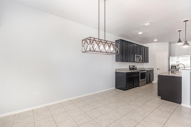 2217 Heaton St, Forney, TX 75126 - kitchen with stainless steel appliances, dark cabinetry, light tile patterned floors, a sink, and recessed lighting
