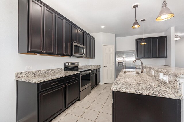 kitchen featuring stainless steel appliances, a sink, light tile patterned flooring, pendant lighting, and a center island with sink