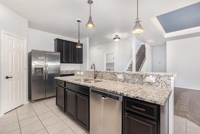 kitchen with appliances with stainless steel finishes, a sink, light tile patterned floors, a center island with sink, and light stone countertops