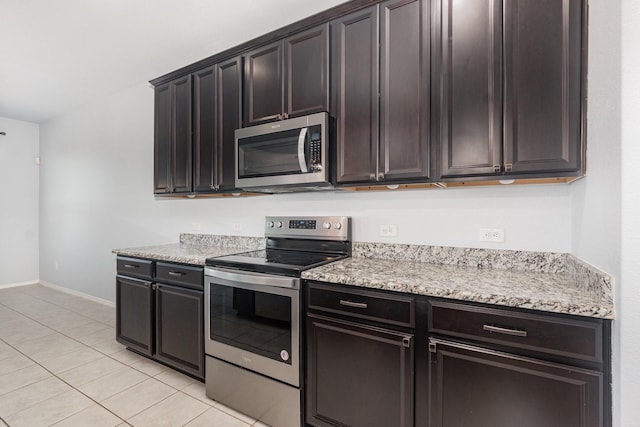 kitchen with stainless steel appliances, baseboards, light tile patterned flooring, dark brown cabinetry, and light stone countertops