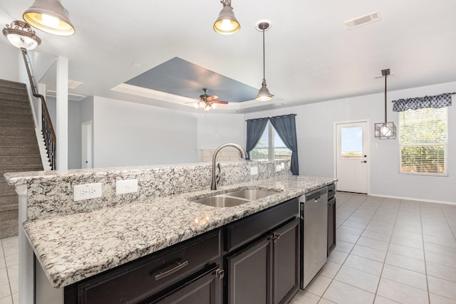 kitchen featuring a sink, dishwasher, light tile patterned flooring, ceiling fan, and a kitchen island with sink